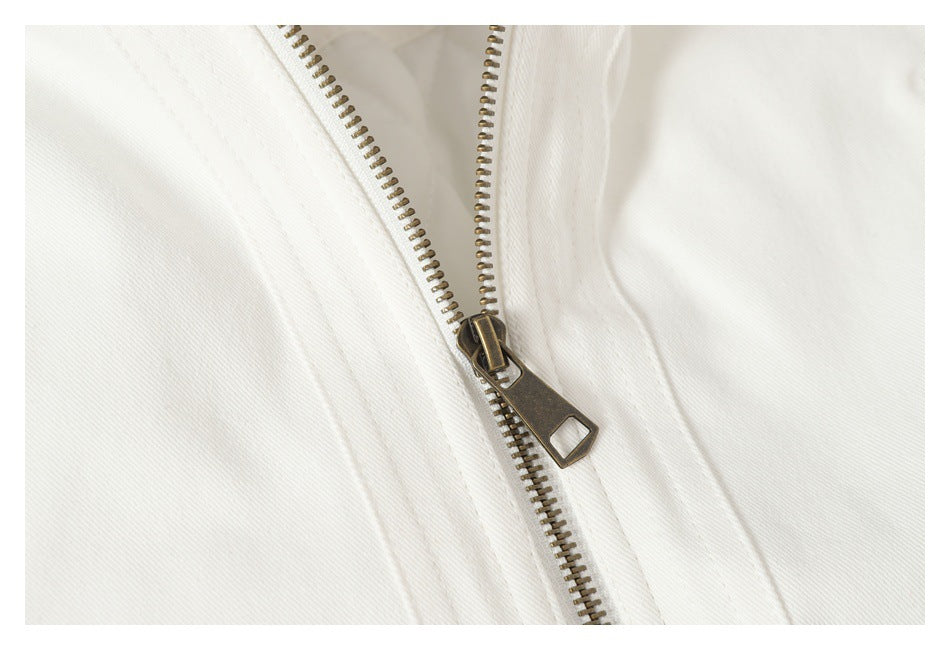 Close-up of the brass-tone zipper and stitching on a white jacket.