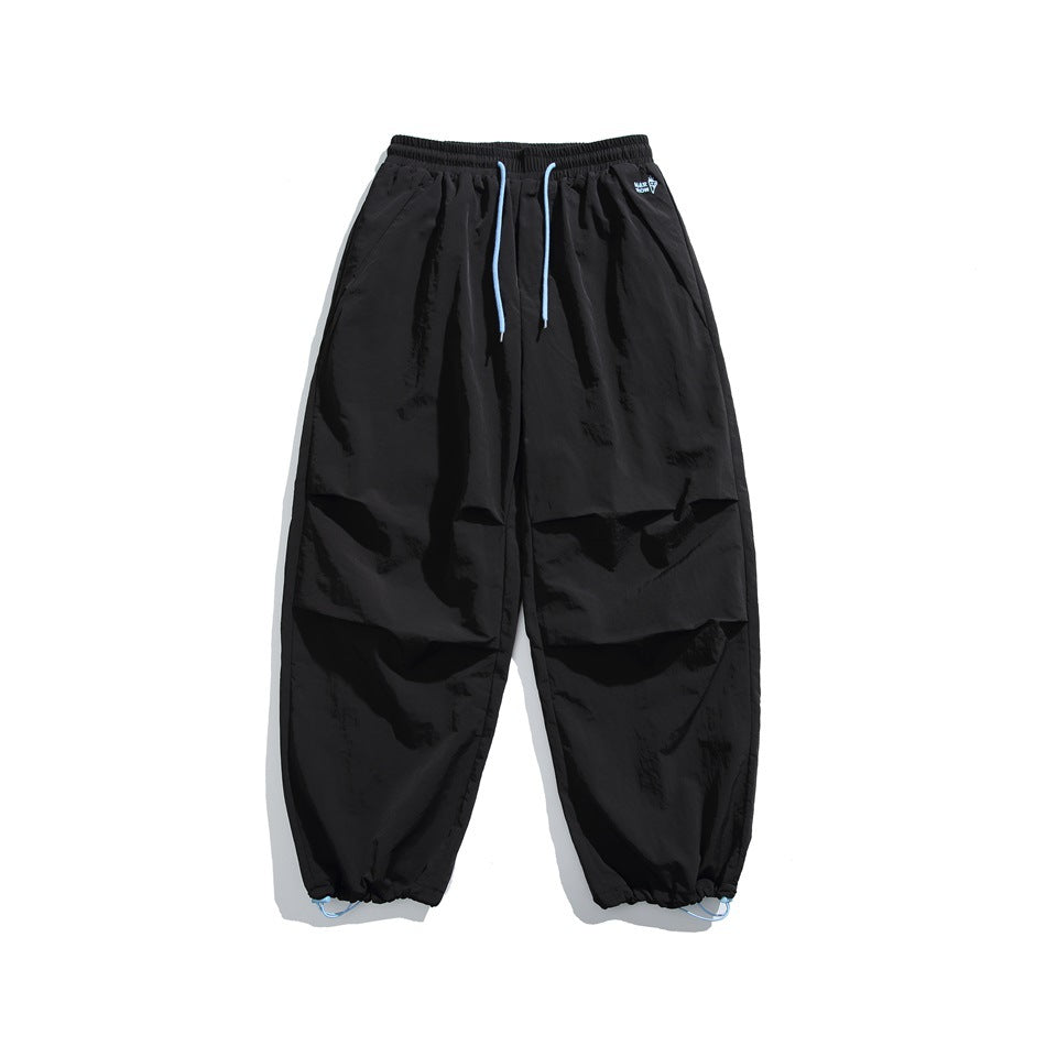 Front view of black jogger pants with light blue drawstrings, side pockets, and adjustable gathered ankle cuffs.