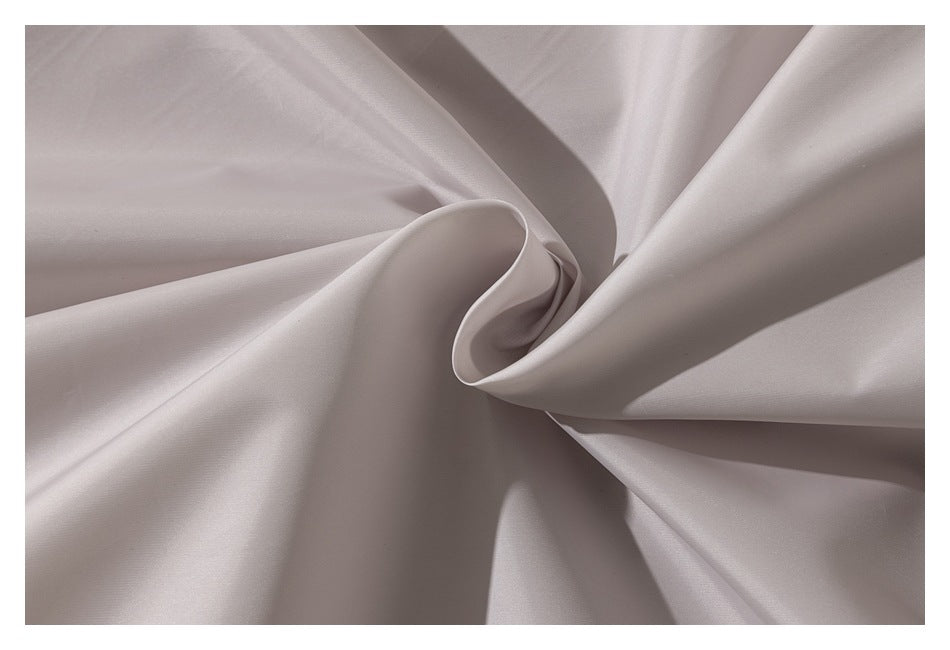 Close-up of smooth pale taupe fabric arranged in soft folds.