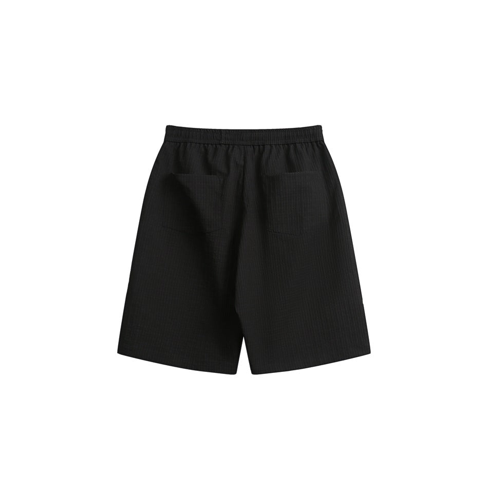 Back view of black shorts with an elastic waistband and two patch pockets.