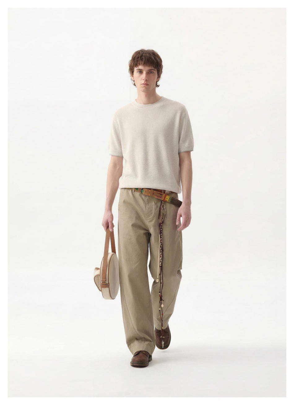 Full-length view of a man in an off-white ribbed knit short-sleeve top and khaki trousers