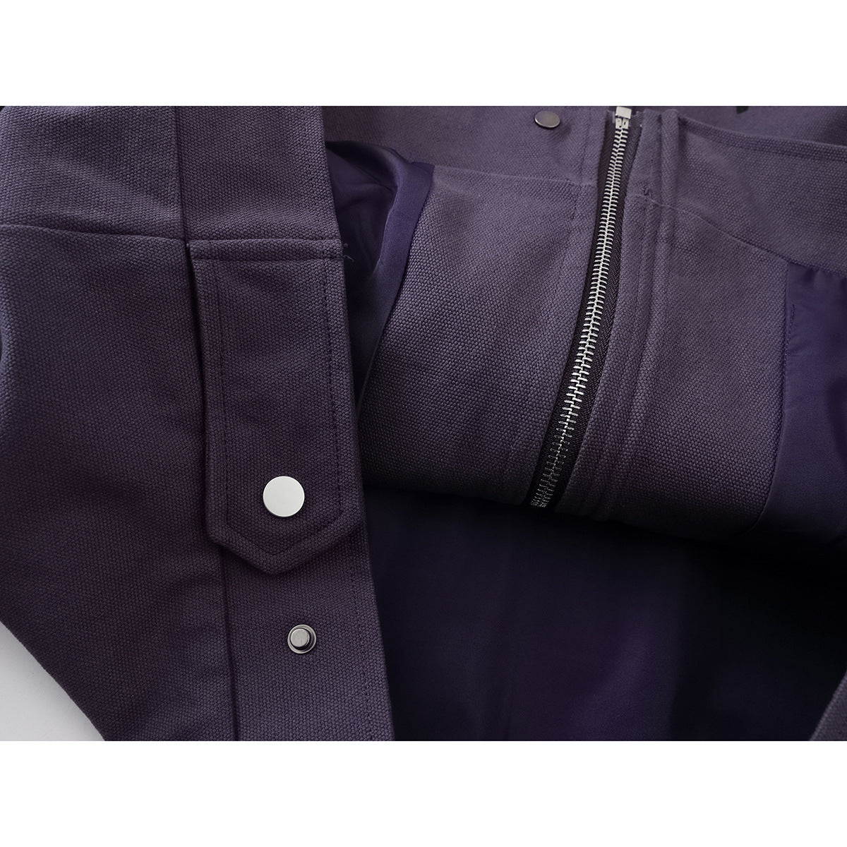 Close-up of a purple jacket's front zipper, snap buttons, placket, and pocket details.