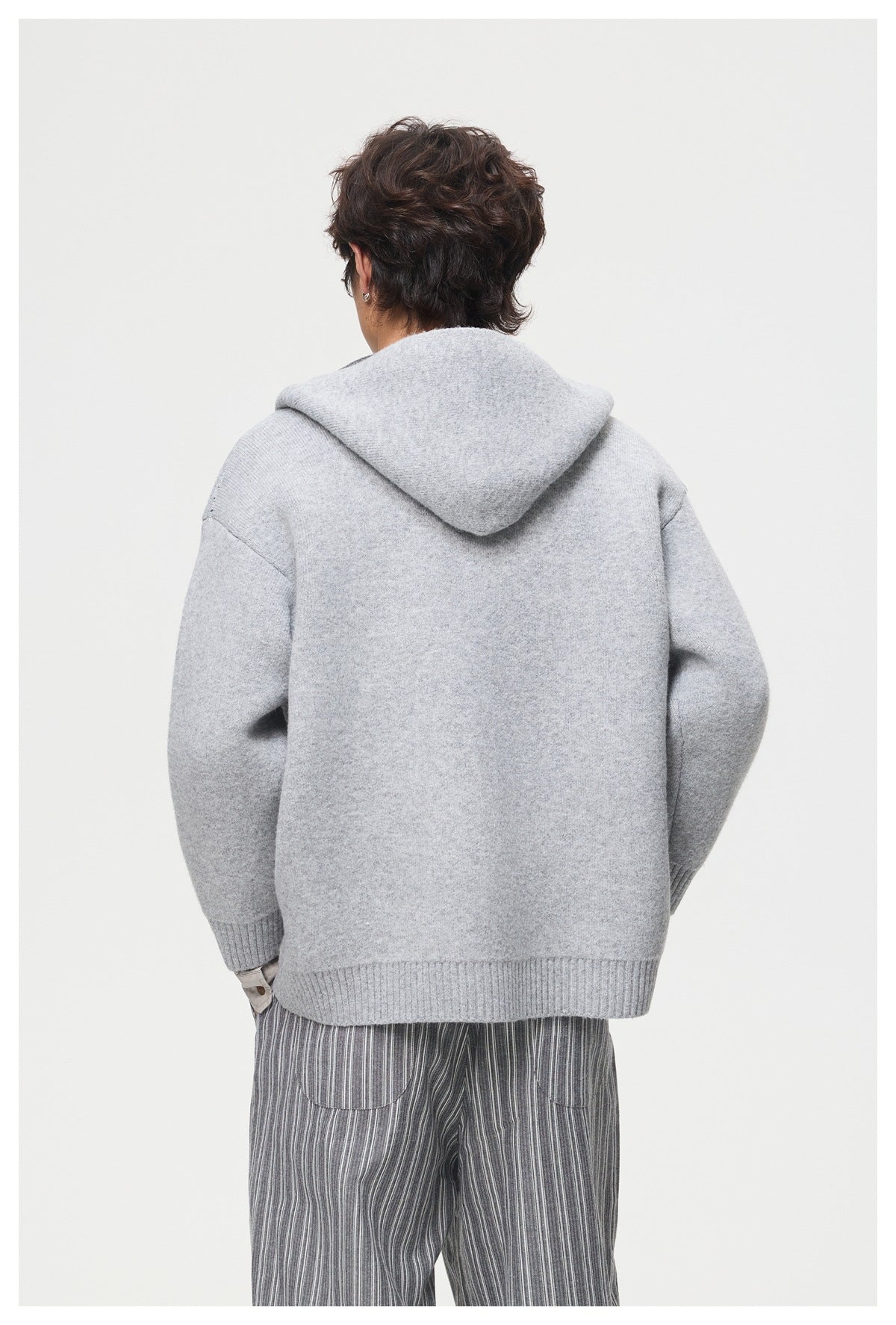 Back view of a model wearing a light gray hooded knit jacket with ribbed cuffs and hem.