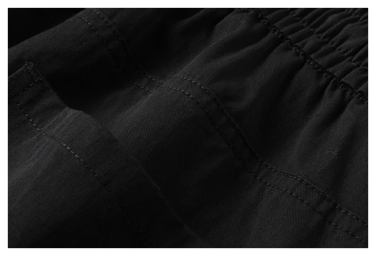 Close-up of black fabric with gathered elastic and rows of stitching.