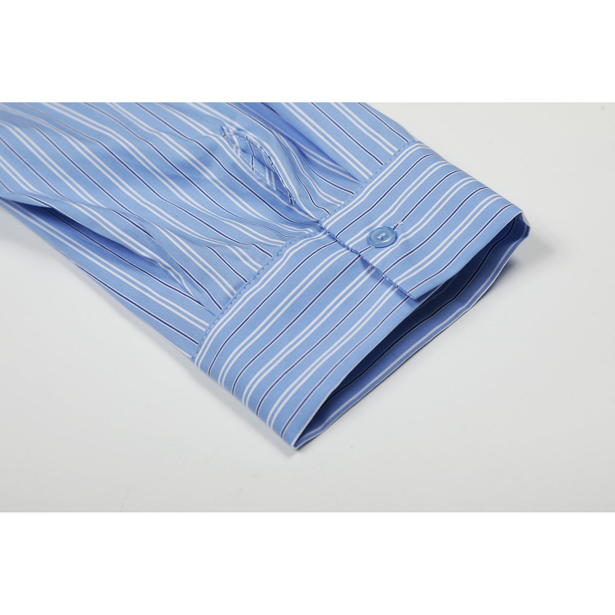 Close-up of a blue-and-white striped shirt sleeve cuff with a button and matching stripes.