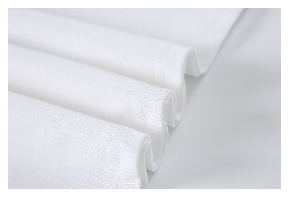 Close-up of several folded white T-shirt edges showing stitched hems.