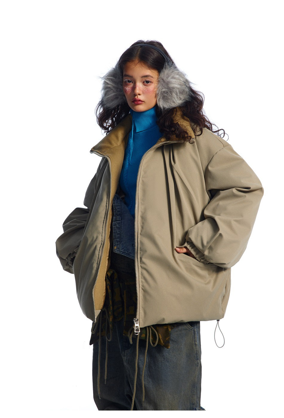Model wearing an open taupe jacket with gray fur-trimmed hood, showing its zipper, roomy sleeves, and drawcord hem.
