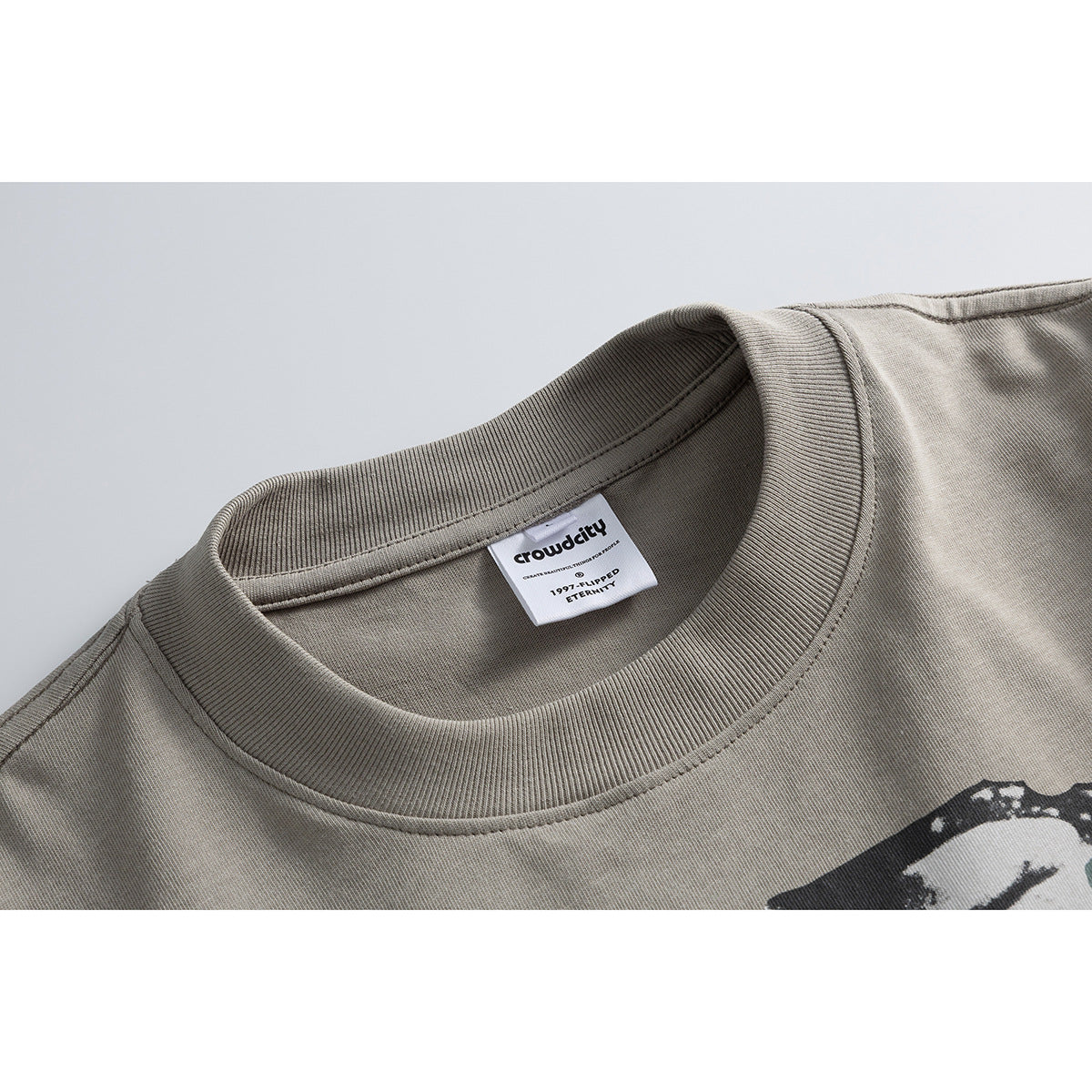 Close-up of a taupe T-shirt’s ribbed crew neckline and sewn-in neck label.