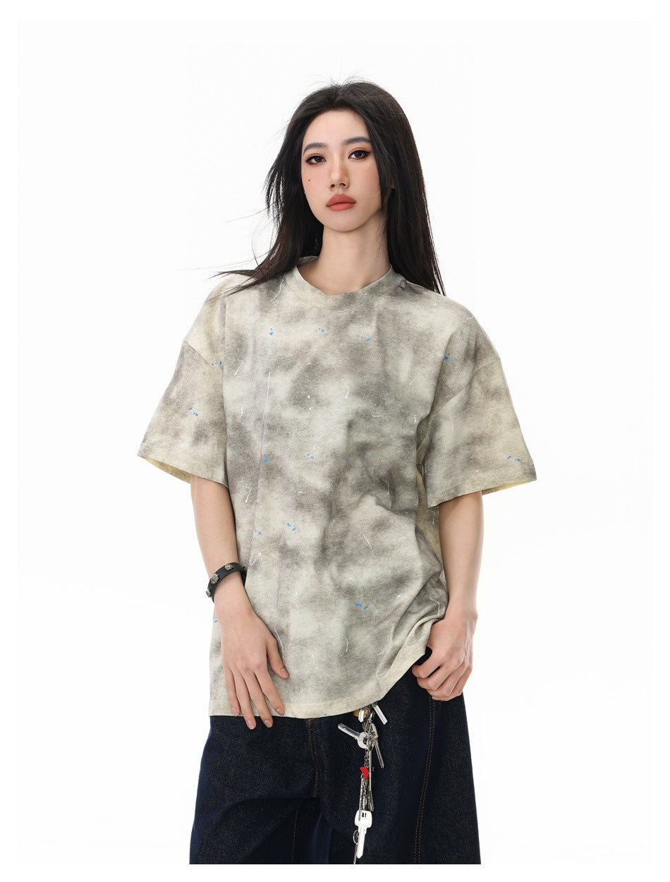 Closer front view of a model wearing a beige-gray mottled oversized T-shirt with scattered flecks.