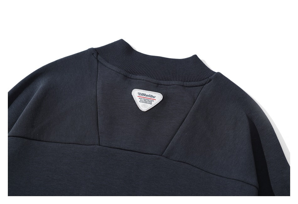 Close-up of the pullover's upper front seams, ribbed collar, and inner neck label.