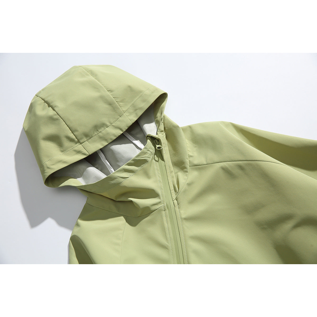 Close-up of a pale green hooded jacket showing its hood lining, collar and front zipper.