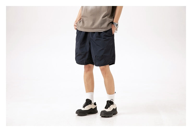 Front view of a person wearing dark navy knee-length shorts with a taupe top.