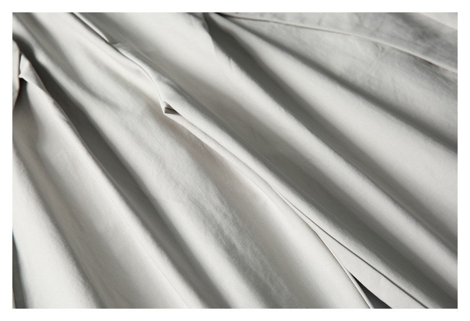 Close-up of light gray trouser fabric and a long stitched front pleat.