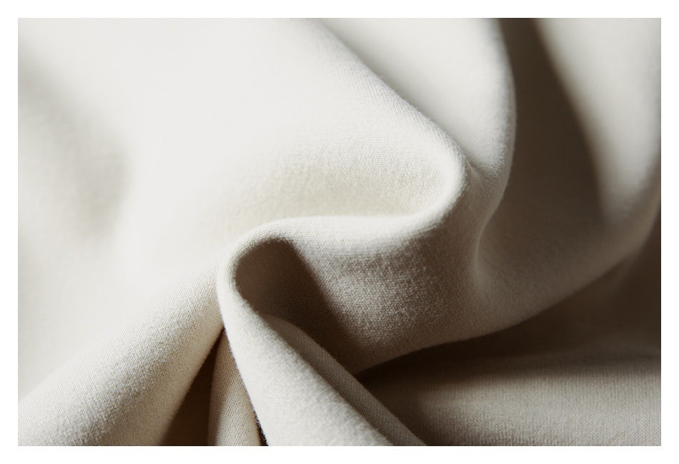 Close-up of softly folded ivory garment fabric, showing its fine surface texture.