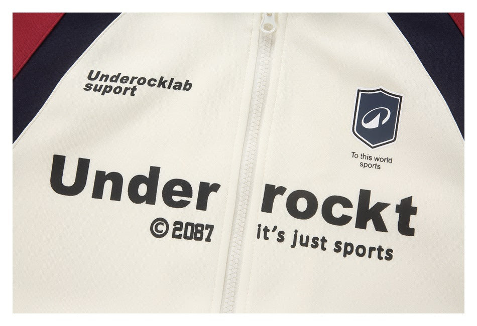 Close-up of an ivory zip-front jacket with black printed lettering and a navy shield emblem.