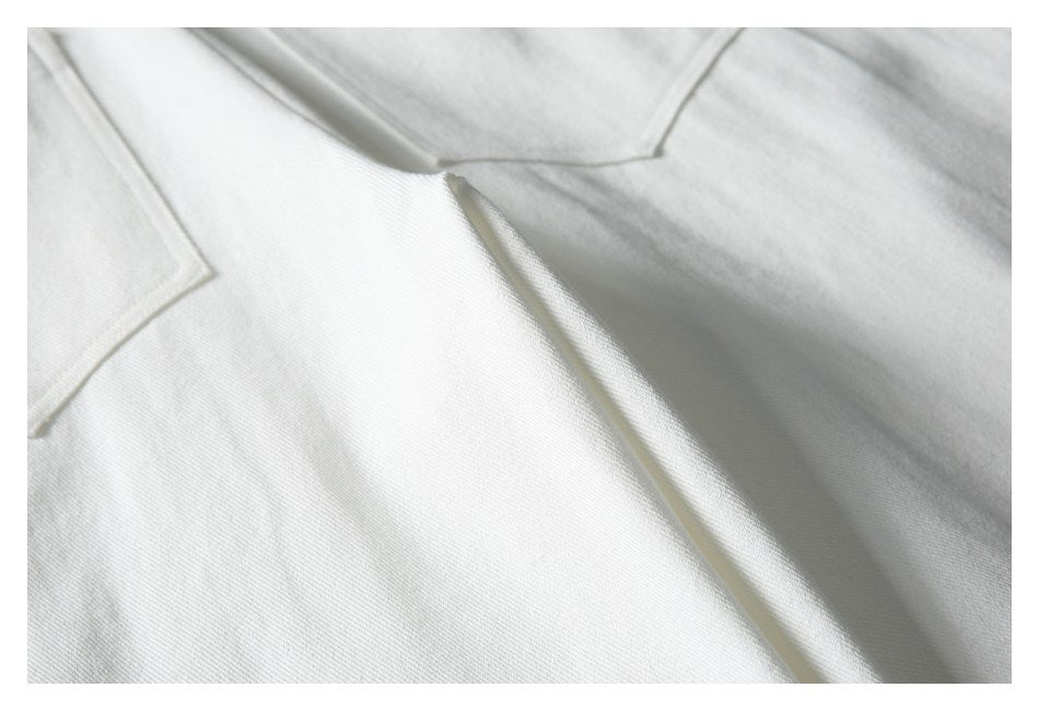 Close-up of white garment panels with angled seams and stitching.