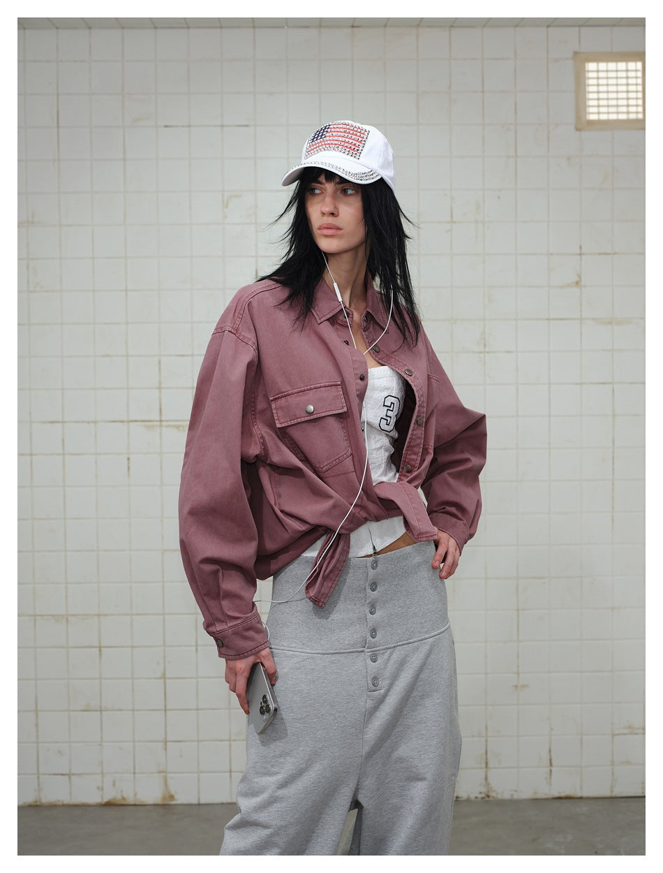 Model wearing an open dusty mauve shirt over a white numbered top and gray pants, with a white cap.