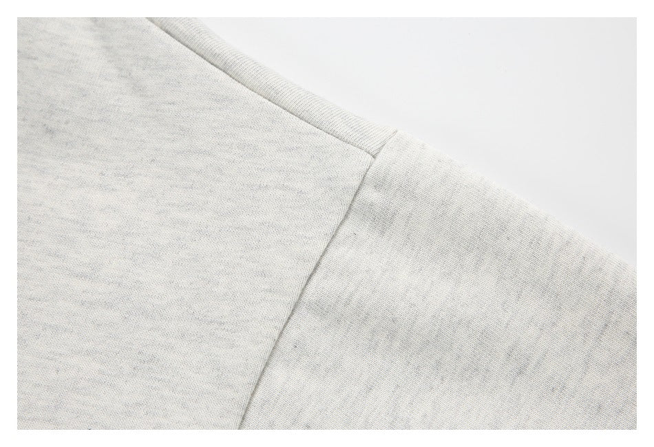 Close-up of the light gray heather shirt's shoulder seam and sleeve stitching.