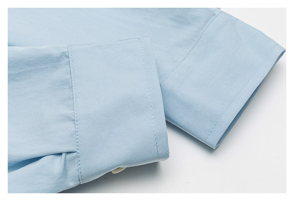 Close-up of the light blue shirt's buttoned sleeve cuff and stitching.