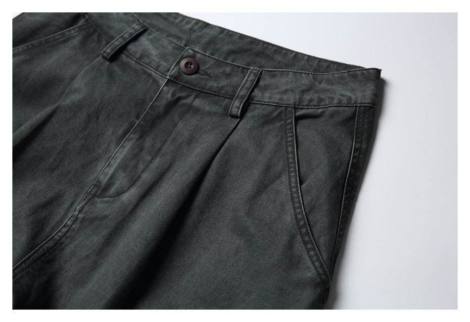 Close-up of charcoal pants showing the waistband, button, belt loops, and curved front pocket.