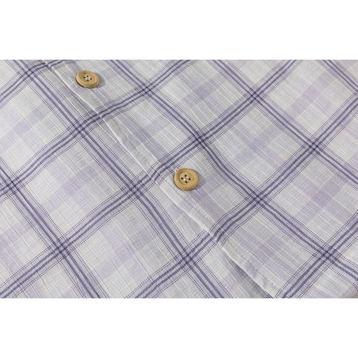 Close-up of pale lavender plaid fabric with two wooden buttons and a stitched placket.