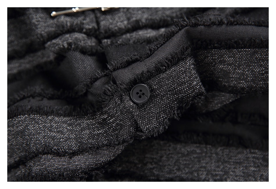Close-up of a black button and frayed trim on the shirt's textured striped fabric.