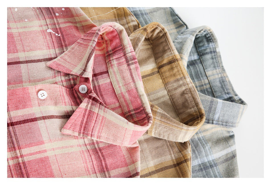 Close-up of pink, tan, and gray-blue plaid shirts arranged to show their collars and buttons.