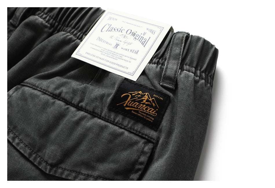Close-up of the charcoal shorts' elastic waistband, rear pocket and attached English-language tags.