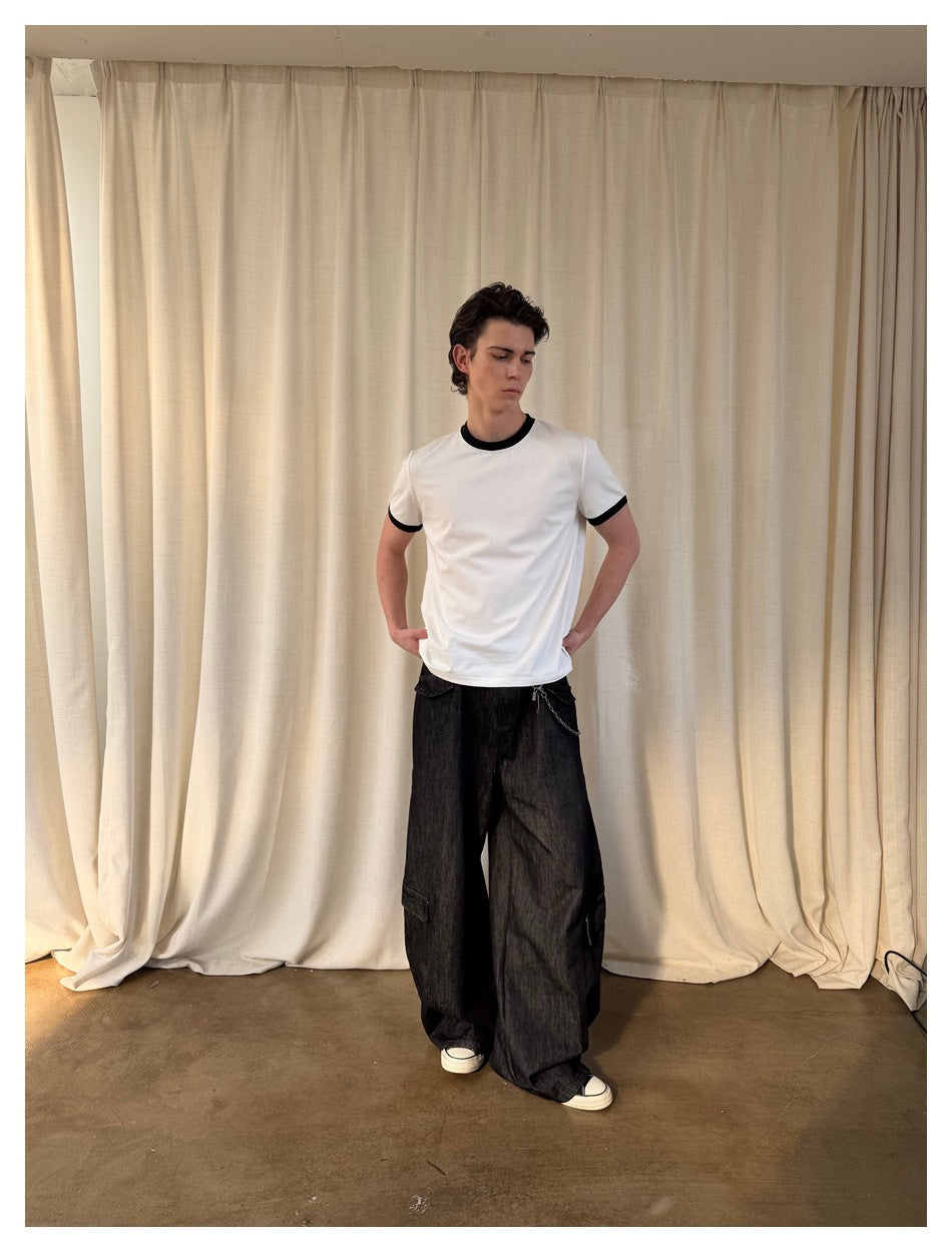 Full-length front view of a model in a white T-shirt with black trim and loose black pants.