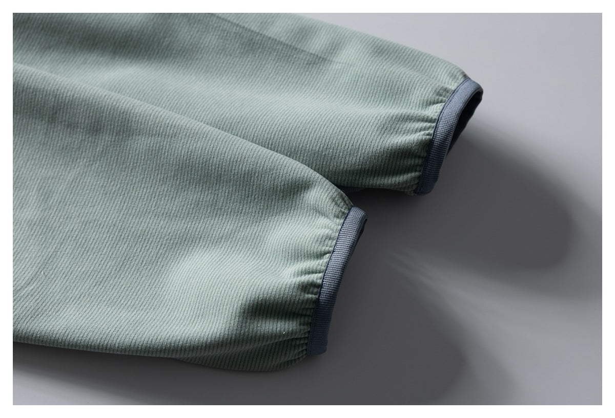Close-up of two sage-green jacket sleeves with dark gray-blue cuffs.
