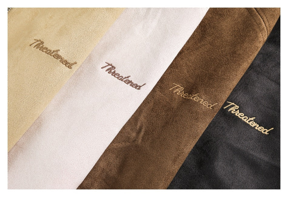 Close-up of four garments in cream, pale pink, brown, and charcoal, each with embroidered script.