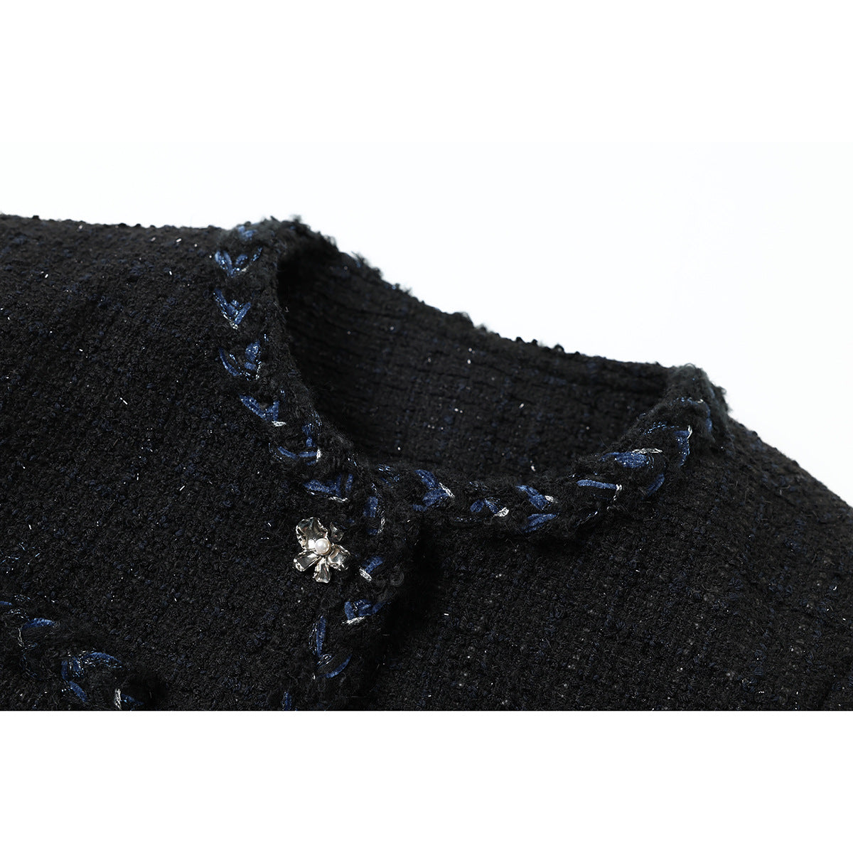 Close-up of a black textured jacket neckline with blue embroidered trim and a small pearl-centered flower ornament.