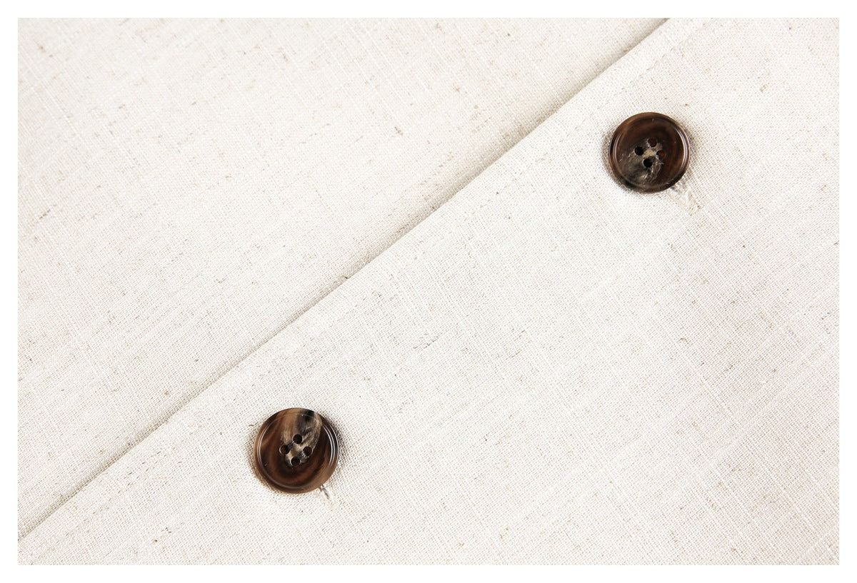 Close-up of two dark brown buttons on the cream jacket's textured fabric.
