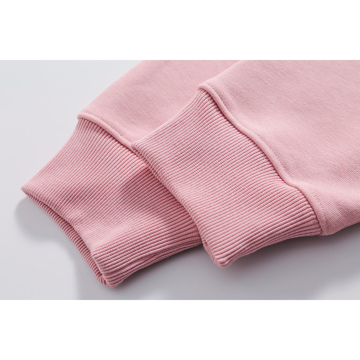 Close-up of a pale pink sweatshirt's ribbed cuffs and sleeve fabric.