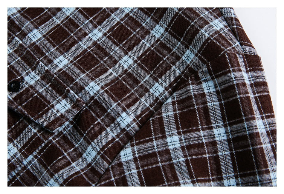 Close-up of the dark brown and pale blue plaid shirt showing a sleeve and buttoned cuff.