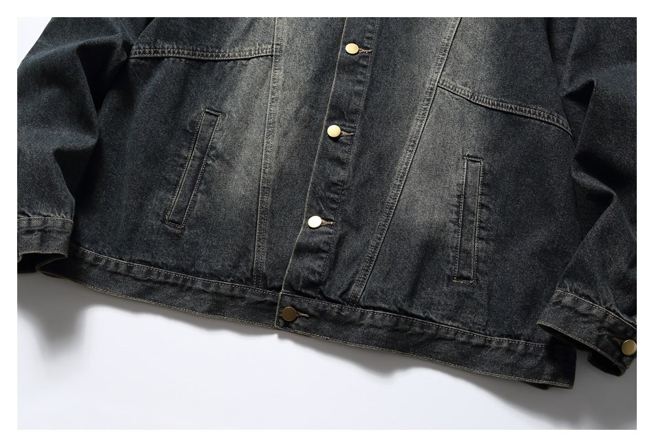Cropped front view of a dark denim jacket showing snap buttons, two angled chest seams, and vertical welt pockets.