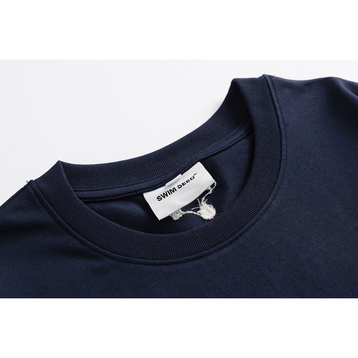 Close-up of a navy T-shirt crew neck and sewn-in white SWIM SEED label.