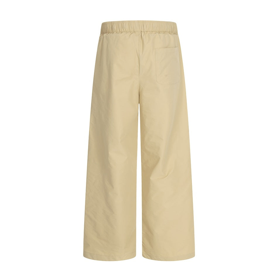 Back view of beige wide-leg pants with an elastic waistband and a single patch pocket.