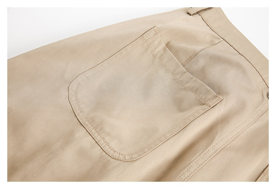 Close-up of a stitched patch pocket on beige trousers.