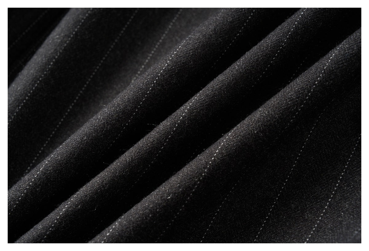 Close-up of black fabric with fine, subtle pinstripes arranged in diagonal folds.