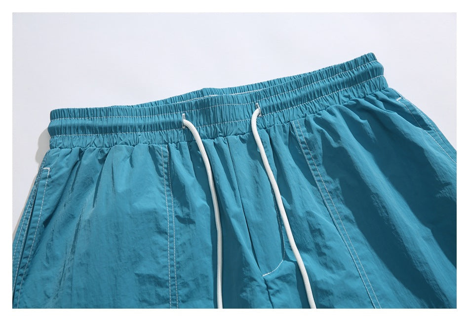Close-up of blue shorts showing the gathered elastic waistband, white drawstrings, and pocket stitching.