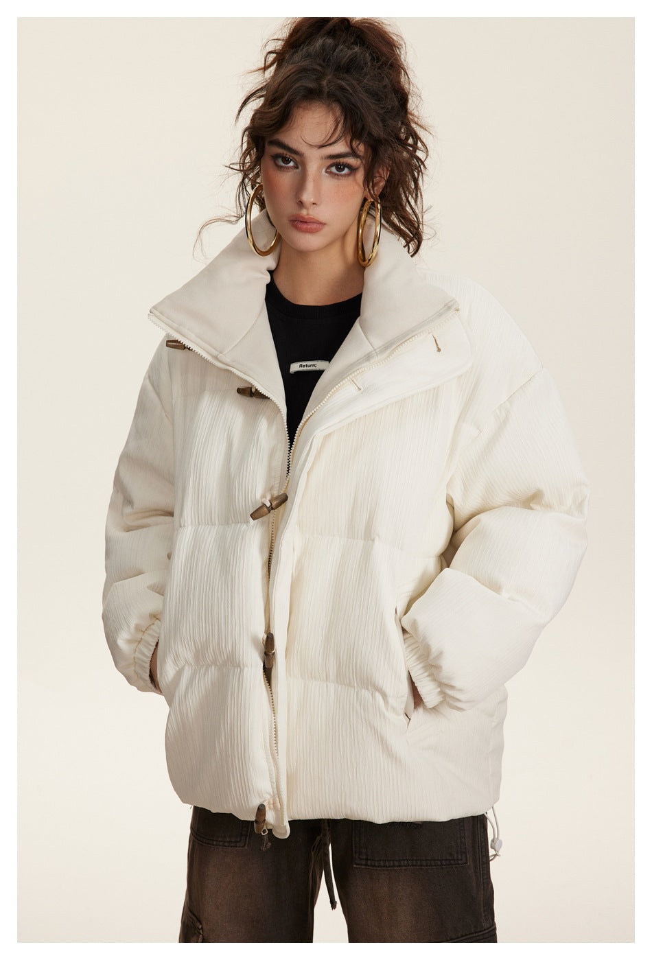 Front view of a model in an ivory quilted puffer jacket with a tall folded collar, toggle closures, and drawcord hem.