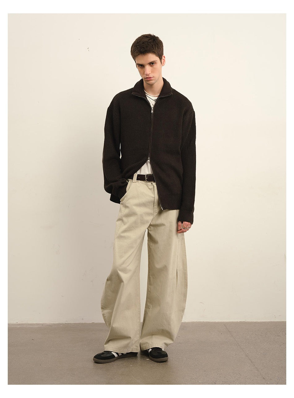 Model wearing a dark brown ribbed zip-front cardigan with a stand collar and wide cream trousers.