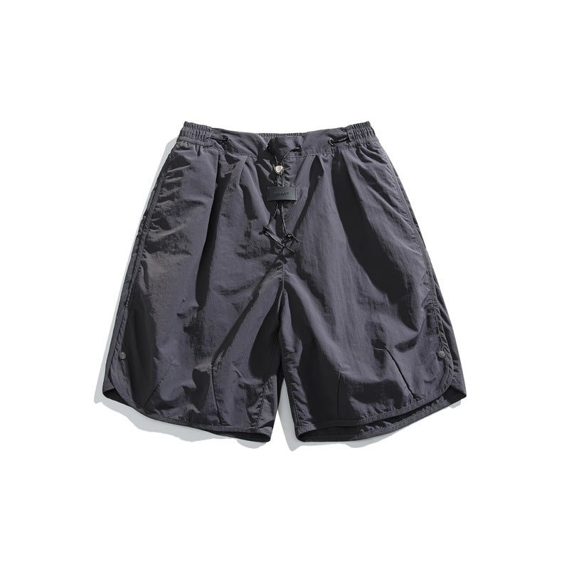 Dark gray loose shorts with drawcord waist, front tag and snap-button curved side hems, flat lay