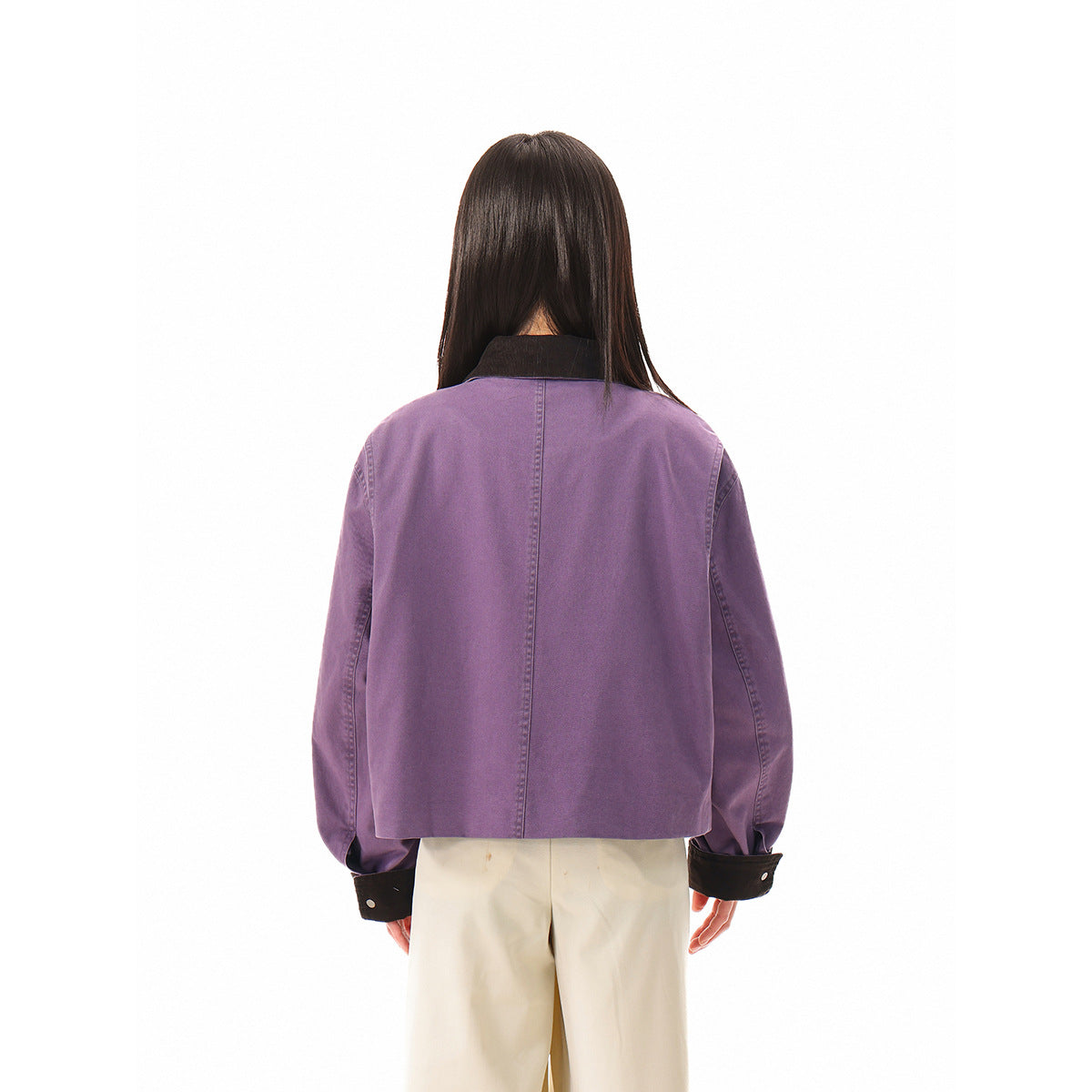 Back view of the lavender jacket, showing its plain back, dark collar and dark cuffs on a model.