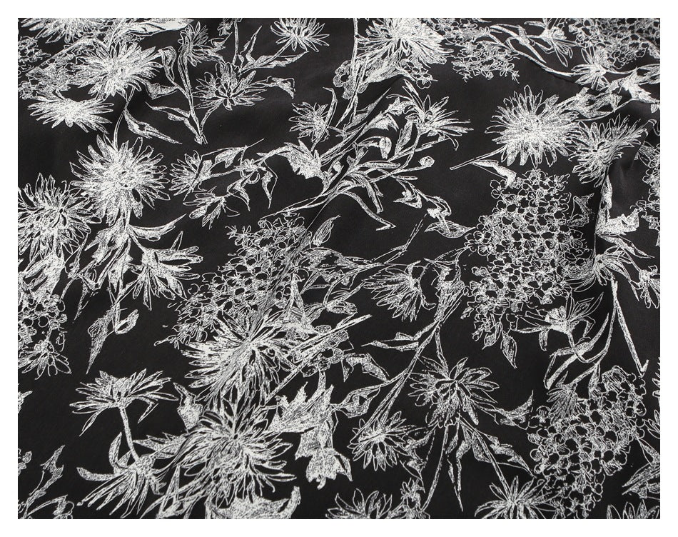 Close-up showing the dense white floral and leaf print on black shirt fabric.