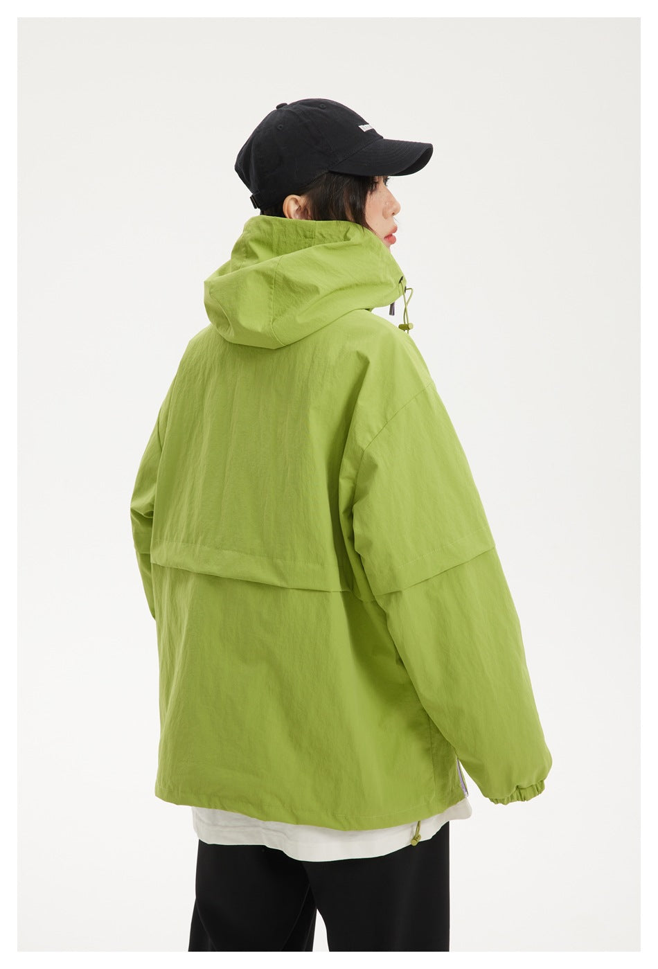 Back view of a model wearing a lime-green hooded jacket with a black cap and elastic cuffs.