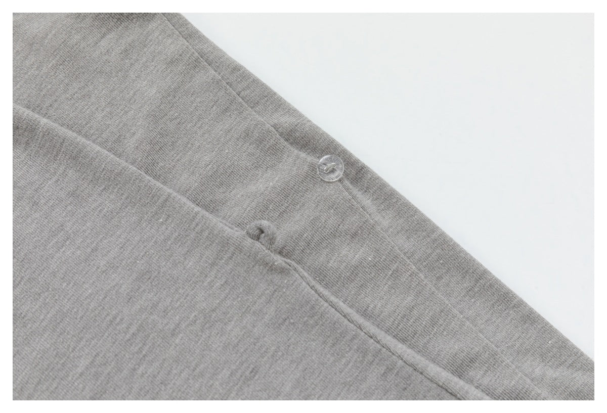 Close-up of a clear button and seam on gray fabric.