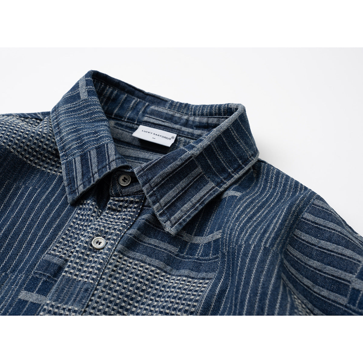Close-up of a blue patchwork-pattern shirt showing its pointed collar, buttons, and textured front placket.