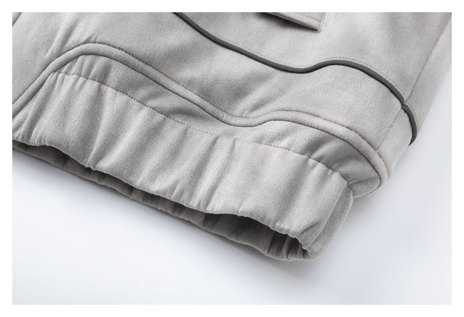 Close-up of the light gray jacket's gathered hem and curved dark piping.